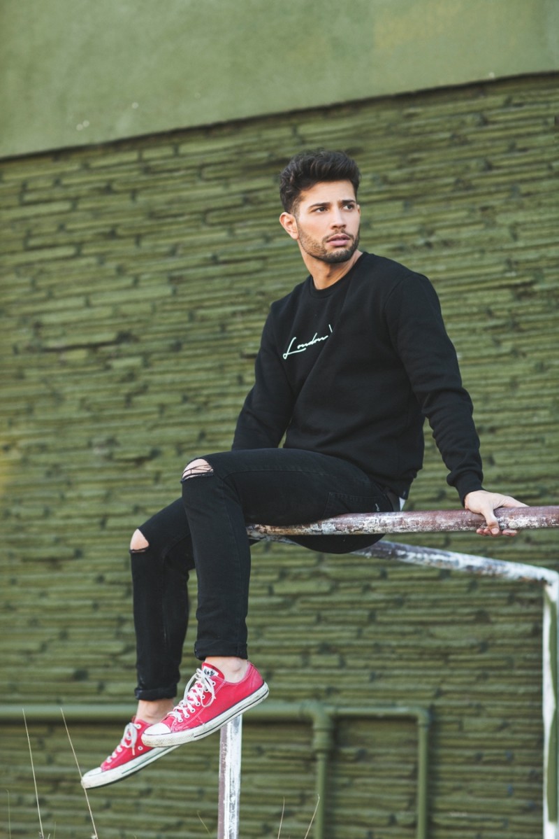 Posing outdoors, Rafael De La Fuente is pictured in skinny denim jeans ripped at the knees.