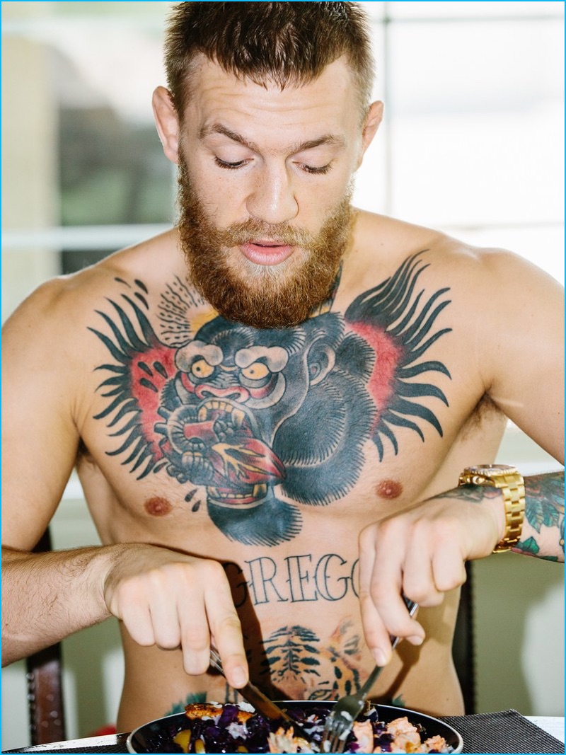 Showing off his signature tattoos, a shirtless Conor McGregor digs into a meal.