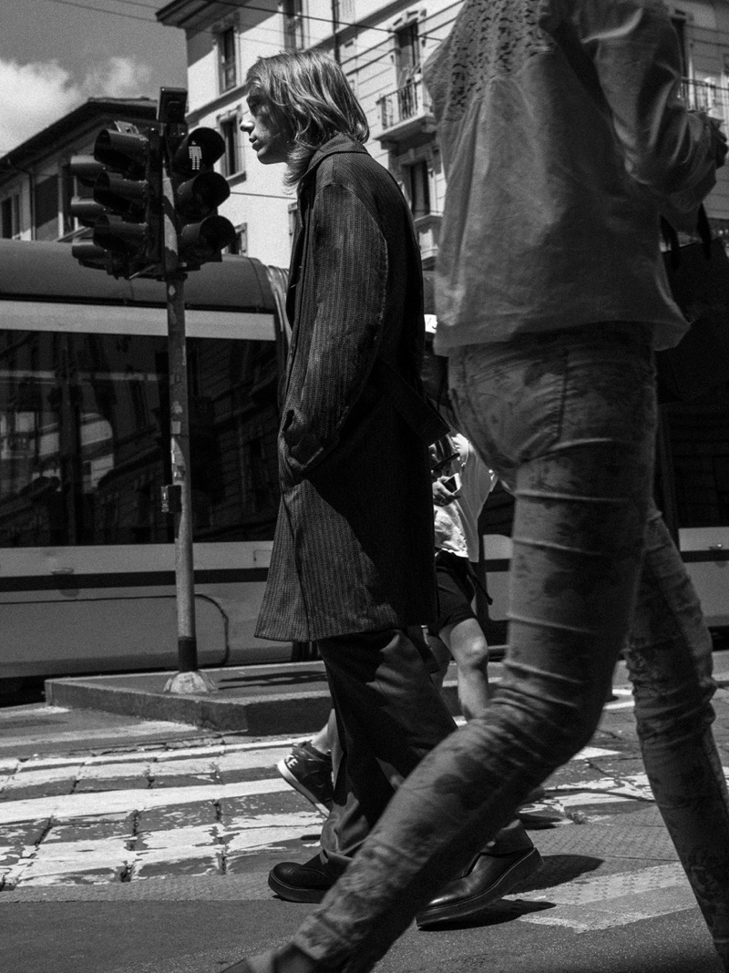 On the move, Mattia Pardini sports a trench coat, sweater, trousers, and shoes from Corneliani. 