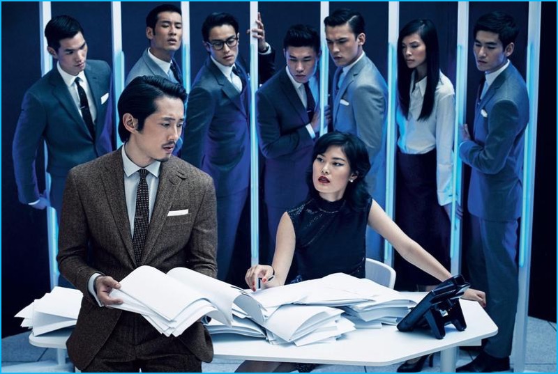 Looking over papers, Steven Yeun wears a Polo Ralph Lauren suit, shirt, and pocket square with an Alexander Olch tie.