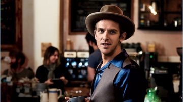 Enjoying a warm beverage at The Fumbally in Dublin, Dan Stevens wears a HUGO Hugo Boss suit with a Visvim shirt, Stetson hat, and Timex watch.