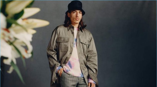 Héctor Bellerín wears a Dries Van Noten oversized shirt with Raf Simons trousers and a tie-dyed sweater by The Elder Statesman. He also sports a Prada bucket hat.