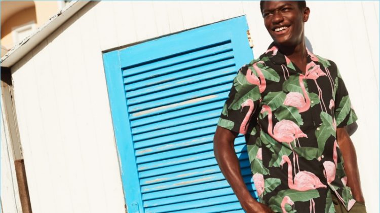 Hamid Onifade reunites with H&M. He wears a relaxed fit flamingo print shirt with cargo shorts.