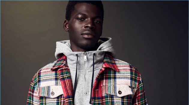 Model Evandro Laurens sports a hoodie with a tartan trucker jacket and trousers by Scotch & Soda.