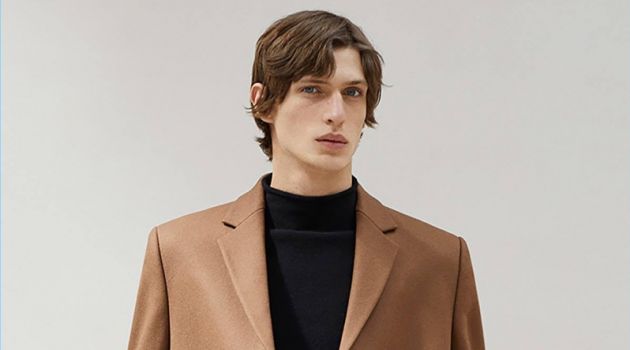 Edoardo Sebastianelli dons a brown coat and mock turtleneck sweater from COS.