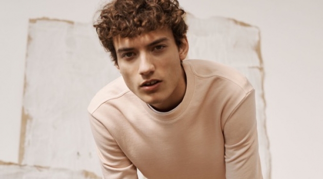 Embracing light hues, Serge Rigvava wears a pink sweatshirt with Connor stretch chinos by Club Monaco.