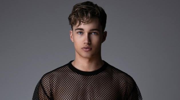 Connecting with Gay Times, AJ Pritchard rocks an oversized mesh tee.