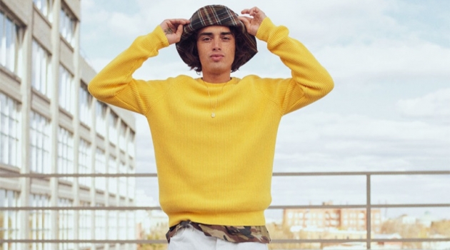 Naleye Dolmans sports a yellow ribbed sweater with a camouflage t-shirt, plaid bucket hat, and pants from Zara.