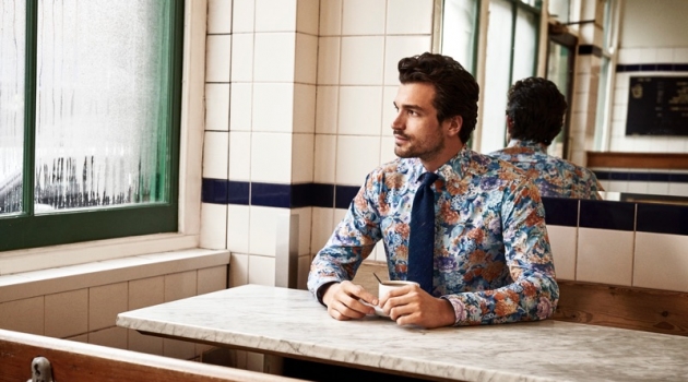 Enjoying a cup of coffee, Paul Kelly models a patterned shirt from Eton's holiday 2019 collection.