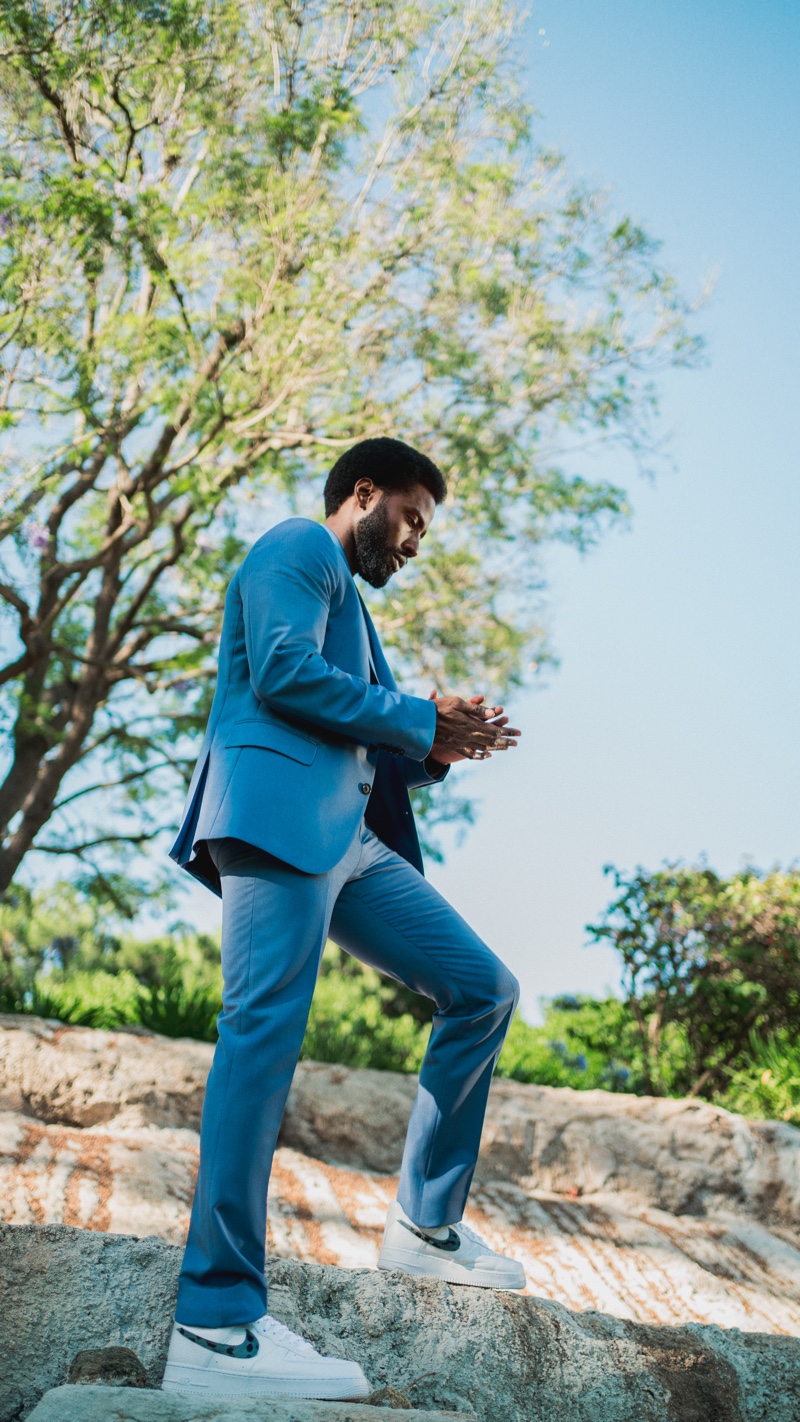 Stepping outdoors, John David Washington sports a Paul Smith suit with a Save Khaki United t-shirt and Nike sneakers.