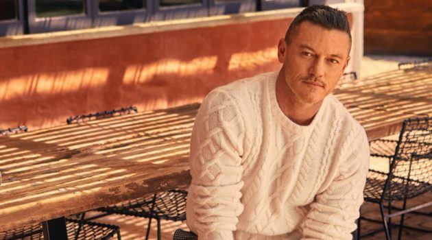 Actor Luke Evans sports a Todd Snyder cable fisherman's sweater in off white with cream and black houndstooth wool pleated pants.