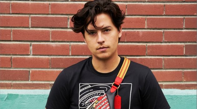 Cole Sprouse rocks a Coach Disney Mickey Mouse x Keith Haring Rivington belt bag with a t-shirt.