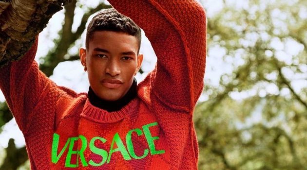 Raphael Balzer dons a logo-adorned argyle sweater for Versace's pre-fall 2021 men's campaign.