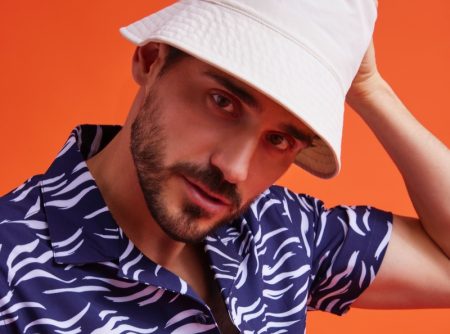 Model Arthur Kulkov embraces a summer vibe in a printed shirt and bucket hat from Onia.