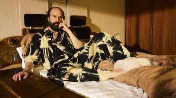 Relaxing in bed, Brett Gelman rocks a SUKU pajama set with Bottega Veneta shearling sandals.