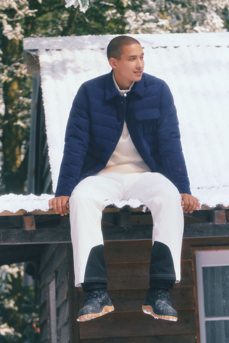 Perched atop a snow-kissed rooftop, Tommy Vanden Meerssche sports a navy quilted Perfect Moment jacket over an off-white sweater.