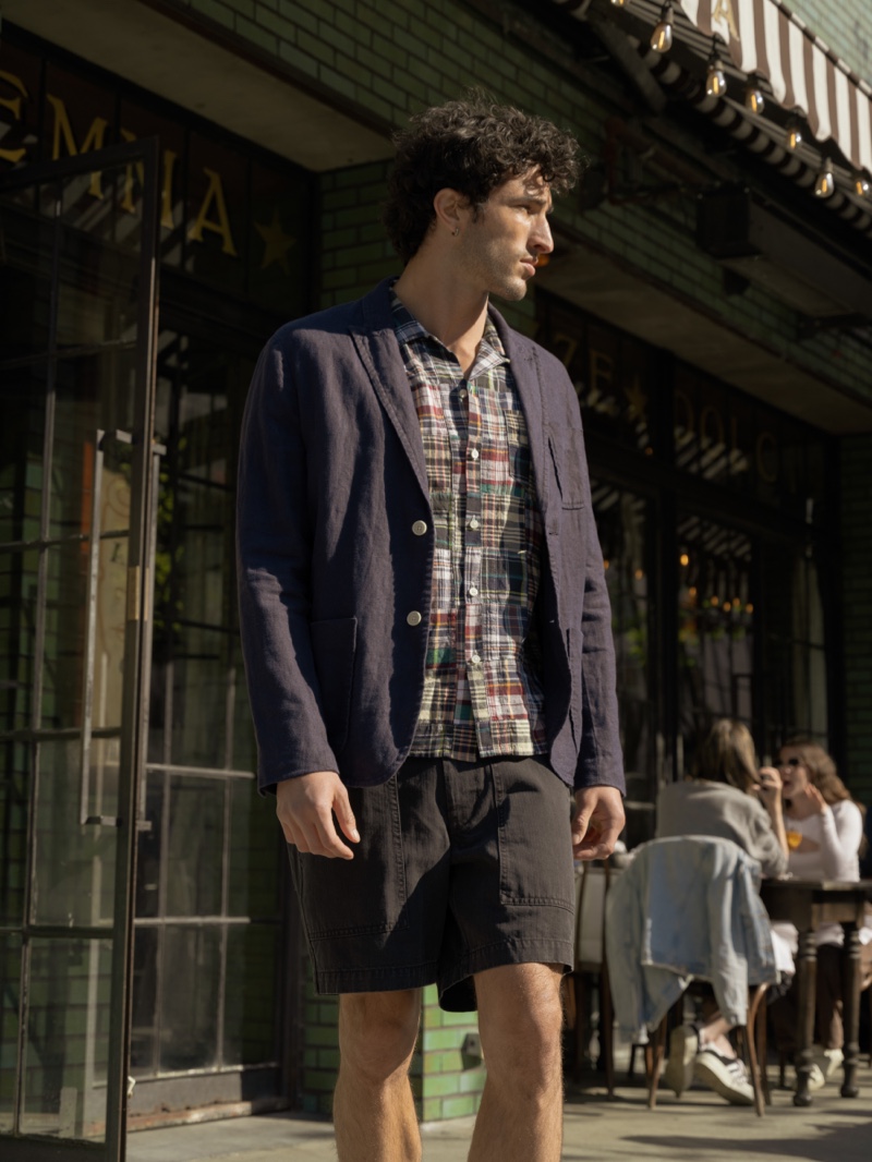 On the move, Raphael Diogo wears an Alex Mill linen blazer, a Madras camp shirt, and herringbone field shorts. 