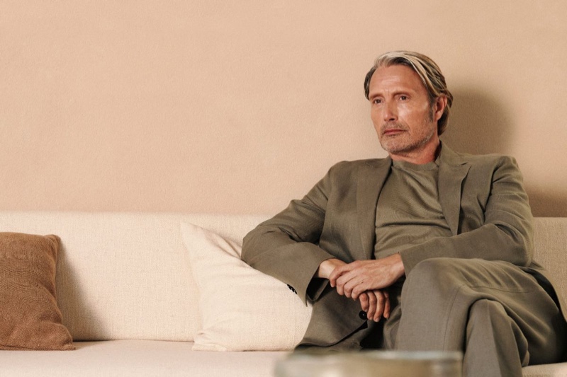 Mads Mikkelsen wears an olive green suit and t-shirt for the Zegna summer 2024 Oasi Lino campaign. 