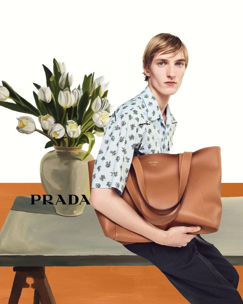 Posing with a leather tote bag, Pierrick Grégoire wears a printed short-sleeve shirt for Prada's summer 2024 campaign.