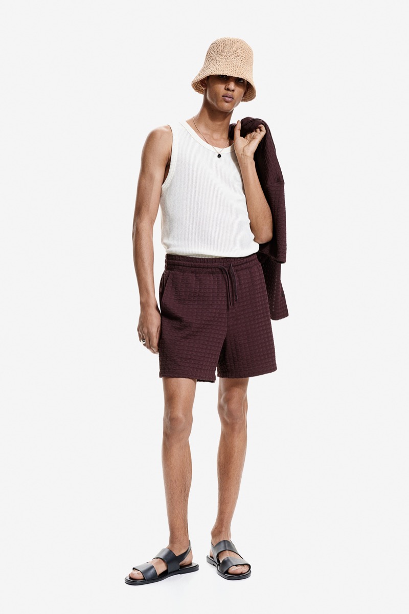 Abas Abdirazaq channels effortless summer style by wearing an H&M knit tank top, textured sweatshorts, and a bucket hat. 
