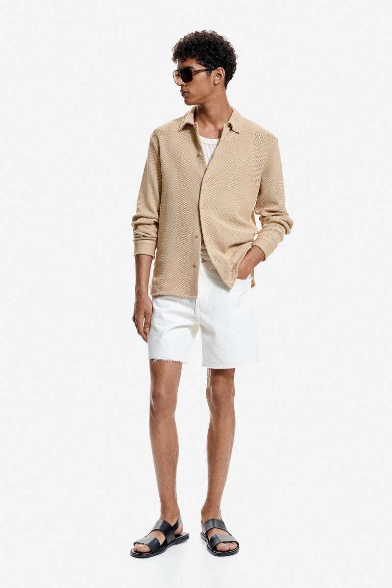 Relaxed summer refinement is displayed as Abas Abdirazaq models H&M's hole-knit shirt with denim shorts.