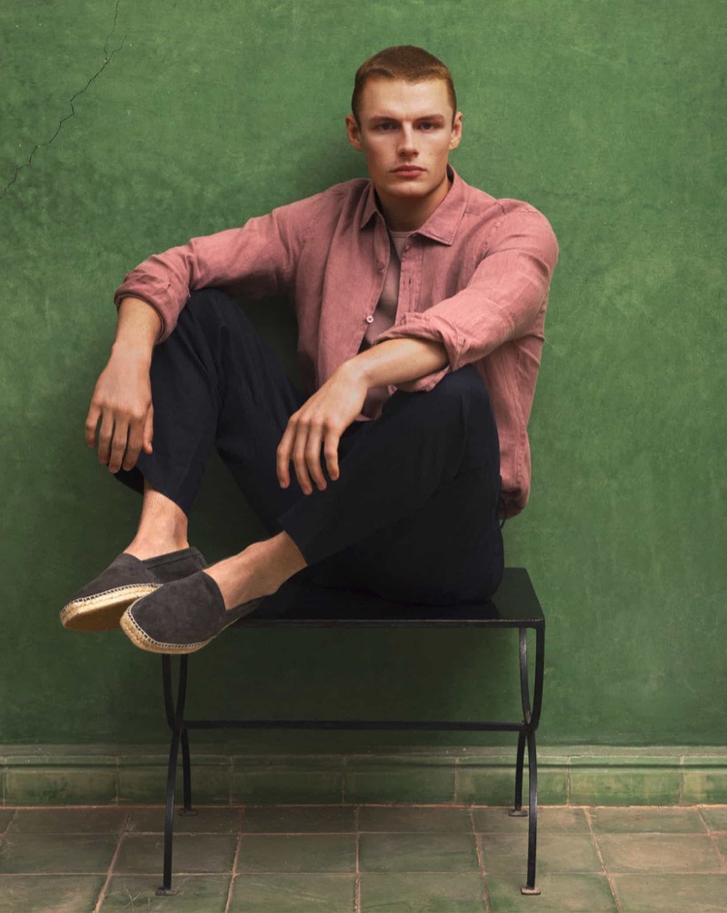 Model Finley Prentice sports Massimo Dutti's summer 2024 collection, featuring a rose-colored linen shirt, dark trousers, and espadrilles. 