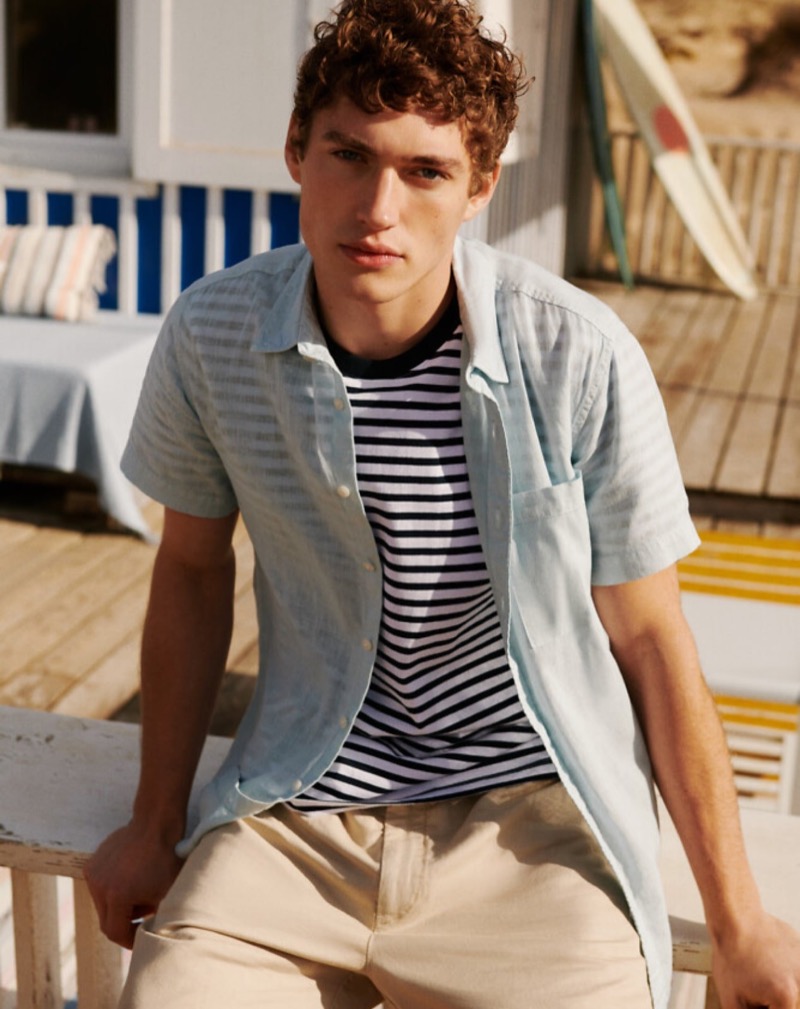 Valentin Humbroich embodies coastal chic, layering a light blue short-sleeve shirt over a classic striped tee from Pepe Jeans' summer 2024 line.