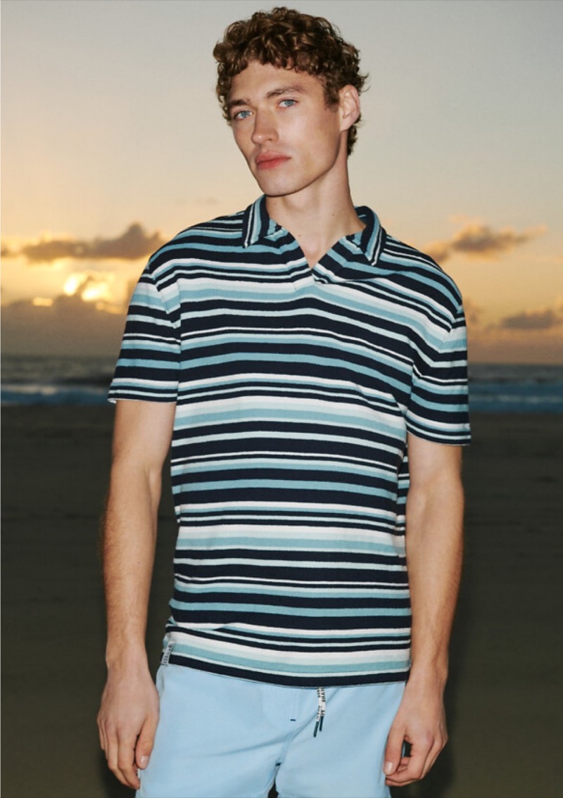 Against a serene sunset, Valentin Humbroich showcases Pepe Jeans' summer 2024 collection in a bold striped polo and light blue shorts. 