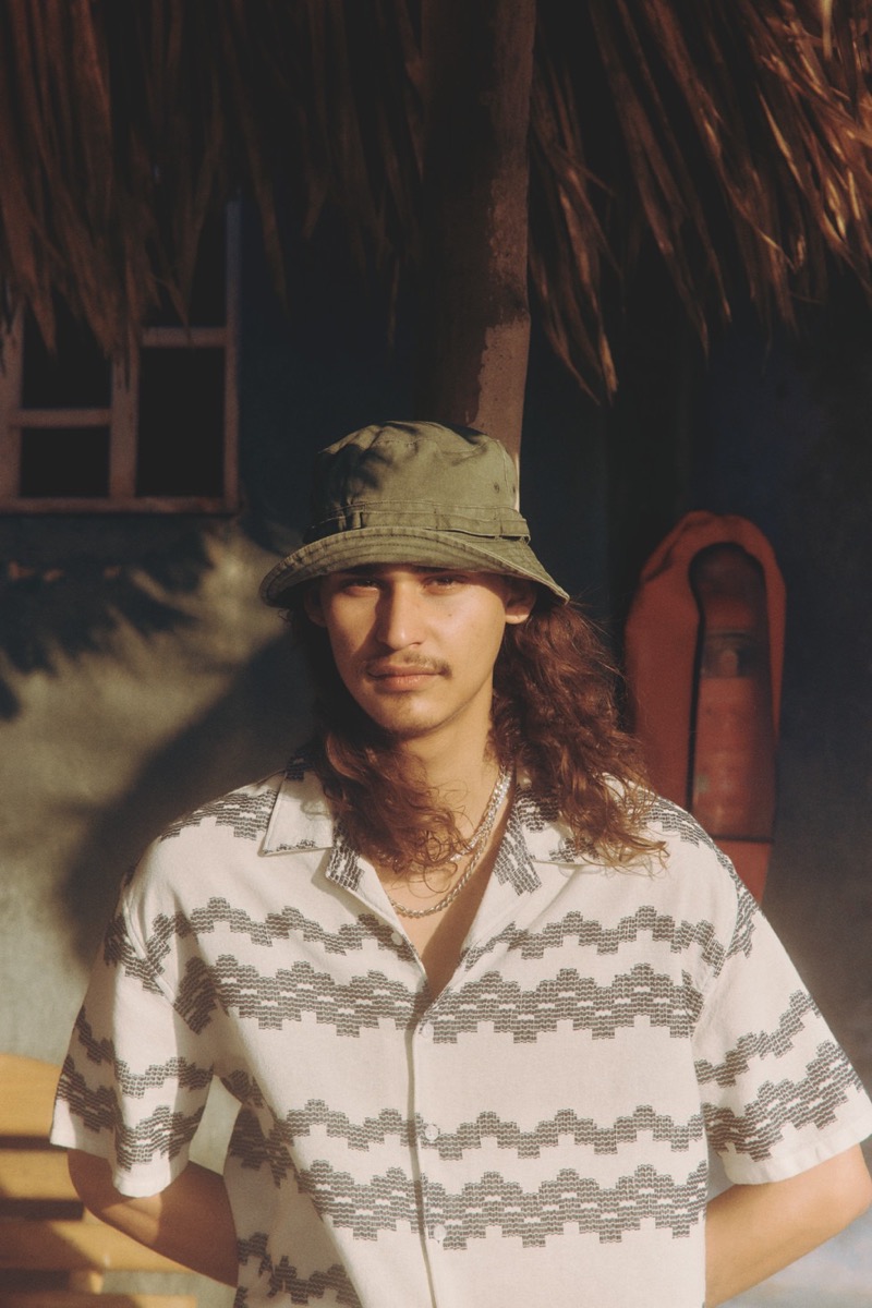 Hudson Primo highlights a relaxed vibe in a print camp shirt and bucket hat from Primark's summer 2024 line. 