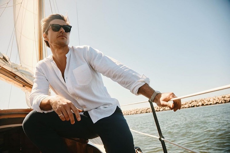 Filip Wolfe embodies nautical elegance in Rails' summer 2024 collection, wearing a white shirt against the backdrop of a sunlit sea. 