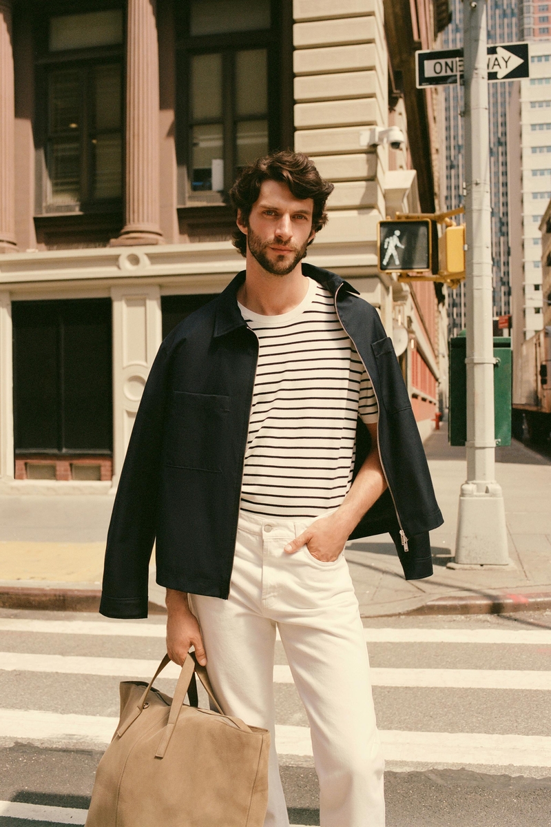 Matthew Bell channels urban cool in Zara’s summer 2024 lineup, pairing a striped tee with white jeans and a jacket over his shoulders.