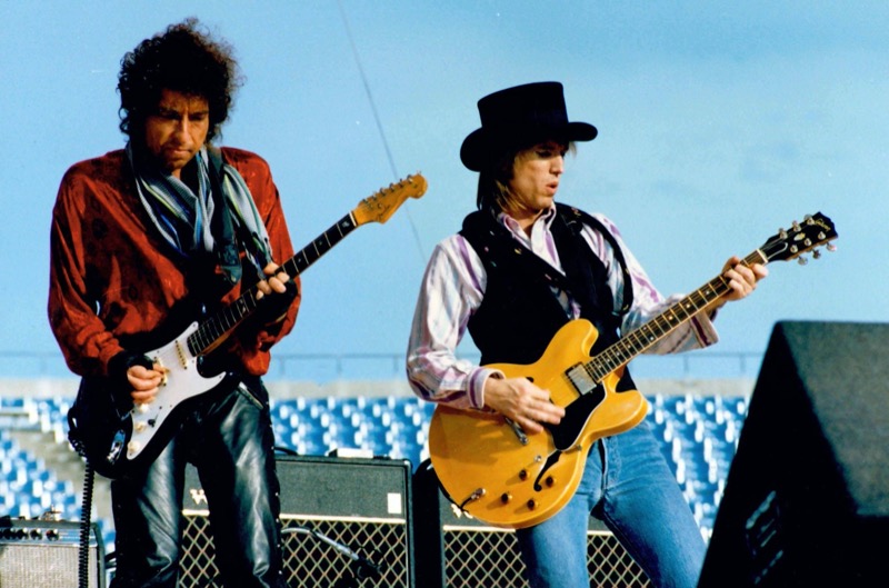 Performing with Tom Petty in 1986, Bob Dylan rocks a red top with leather pants.