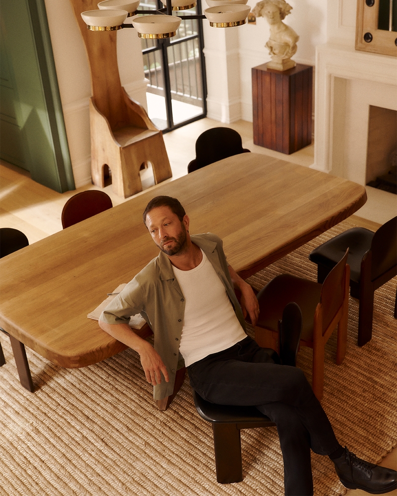 Lounging, Ebon Moss-Bachrach wears a Paul Smith camp-collar shirt and a CDLP ribbed tank top, finished with Officine Creative leather boots.