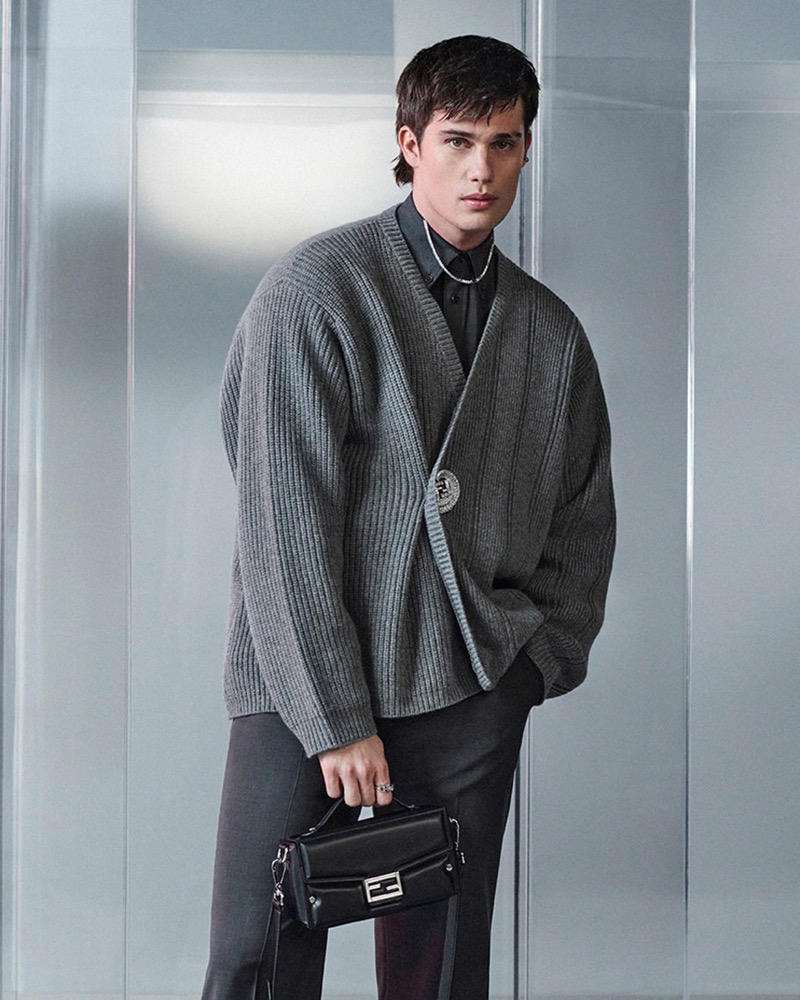 Nicholas Galitzine wears an oversized cardigan with smart trousers, accessorized with a Fendi soft trunk Baguette.