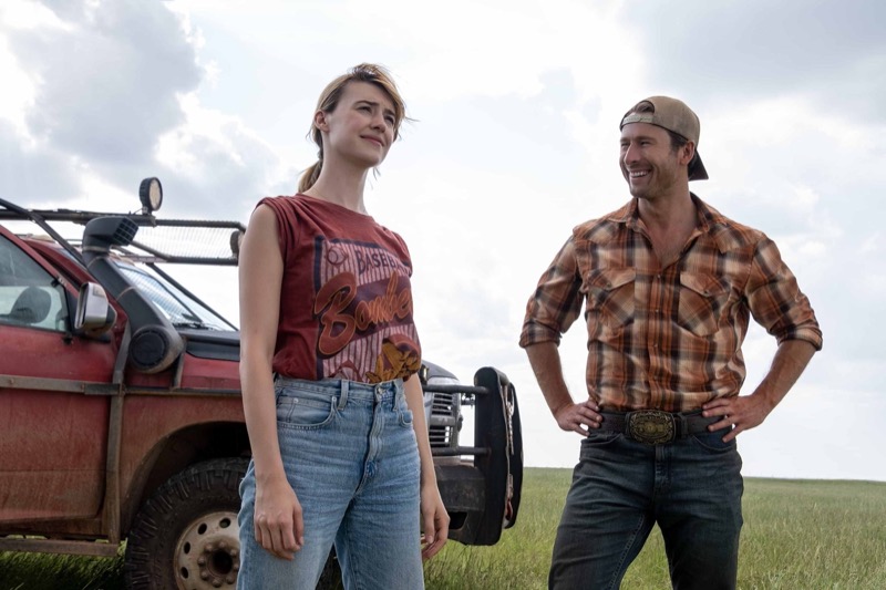 Glen Powell and Daisy Edgar-Jones share a light moment in the field, with Tyler Owens’ plaid shirt adding a rustic touch to the scene in “Twisters.”