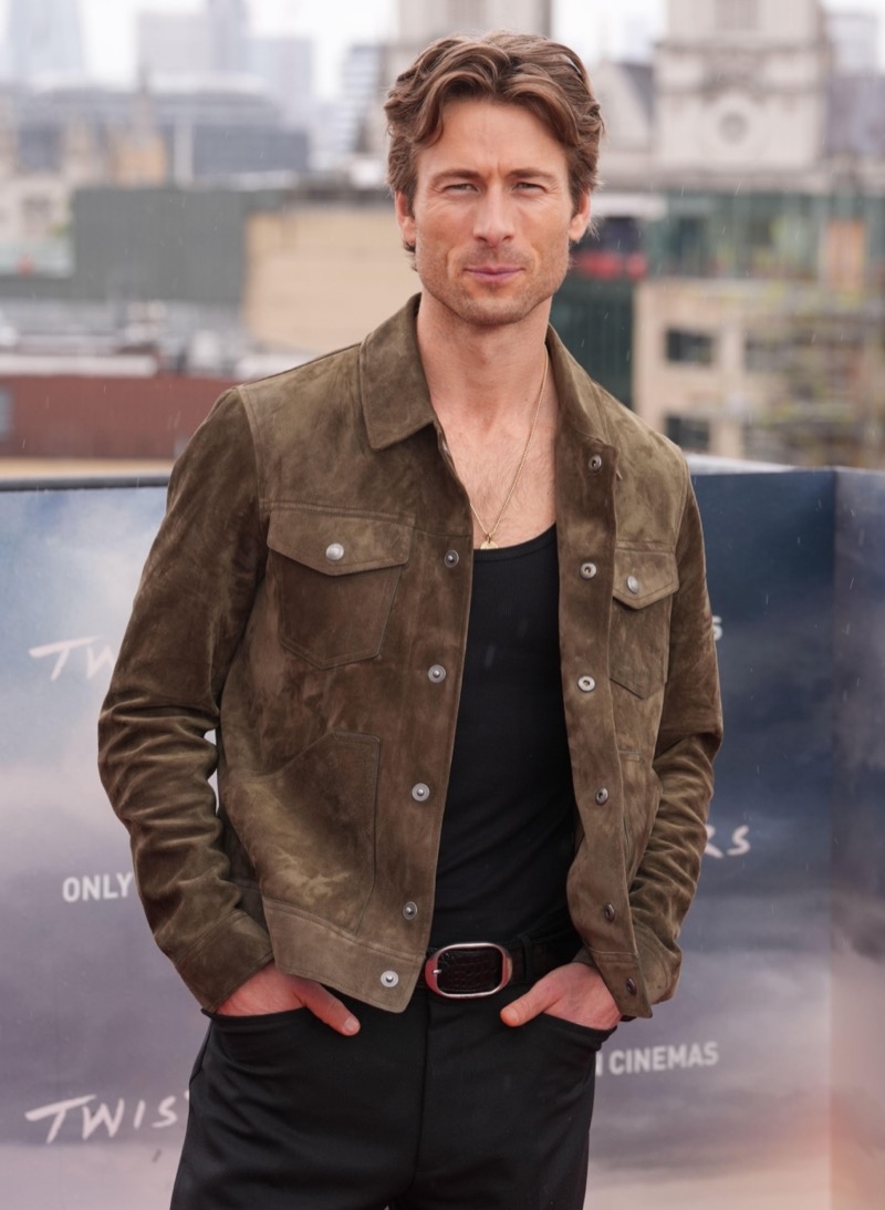 A luxe vision in Tom Ford, Glen Powell sports a brown suede jacket over a black ensemble for a “Twisters” photocall in London.