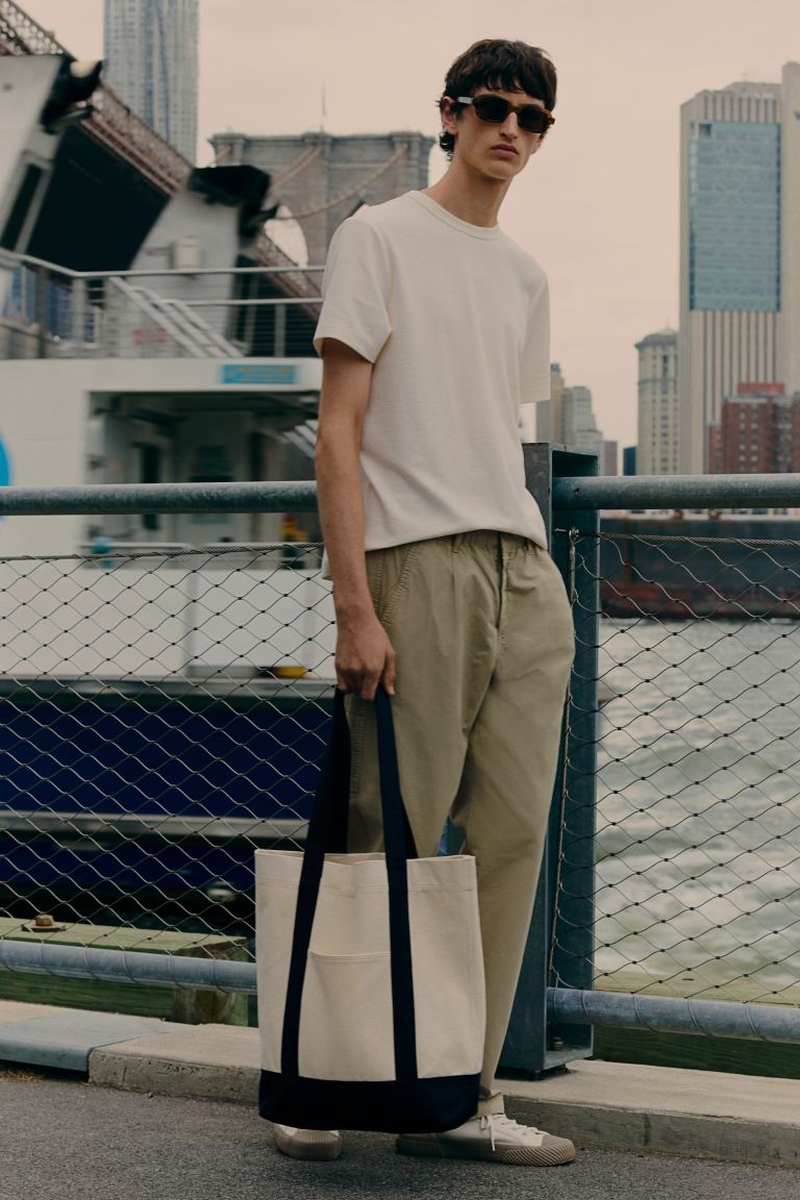 Model Anden Scudder dons a classic white tee and khaki pants by H&M, accessorized by a casual tote.