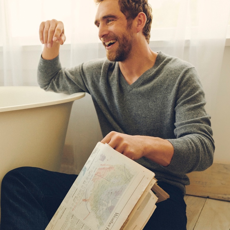 All smiles, Will Chalker dons a cashmere V-neck sweater.