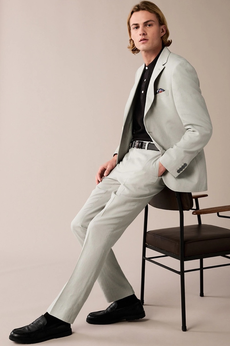 Embrace a world of contrast by pairing a light grey suit with a black polo shirt and accessories.