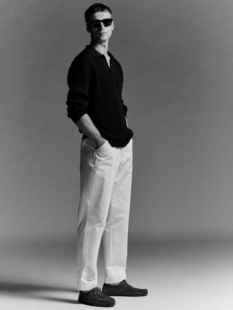 French model Clément Chabernaud dons a black polo sweater and white trousers from Massimo Dutti’s summer 2024 collection.