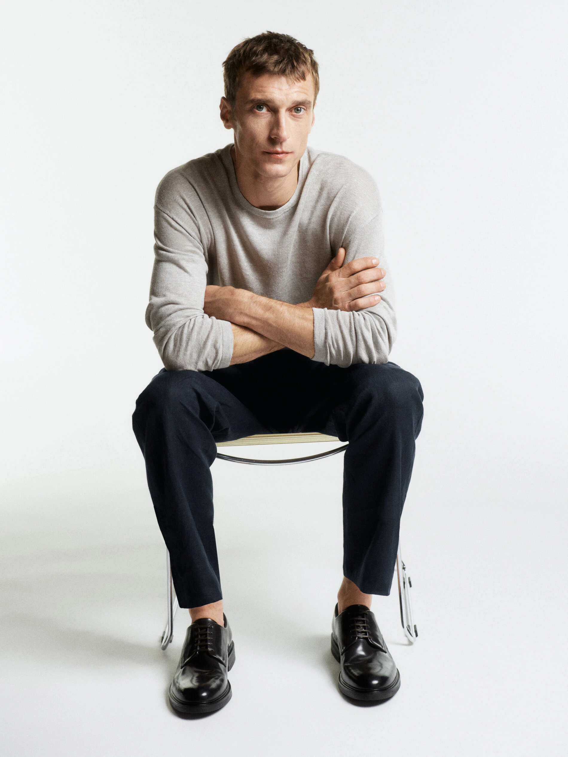 Clément Chabernaud showcases effortless charm in a light grey sweater and dark trousers from Massimo Dutti’s summer 2024 collection.