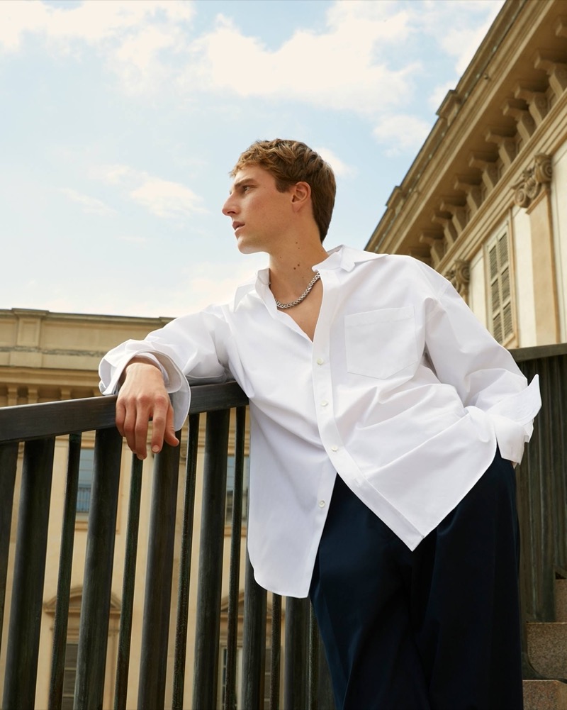 Embracing simplicity, Quentin Demeester leans casually in a crisp white Gucci shirt. 