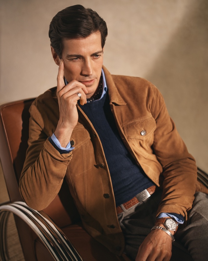 Oriol Elcacho models a Polo Ralph Lauren suede trucker jacket over a navy cable-knit sweater with pleated trousers. 