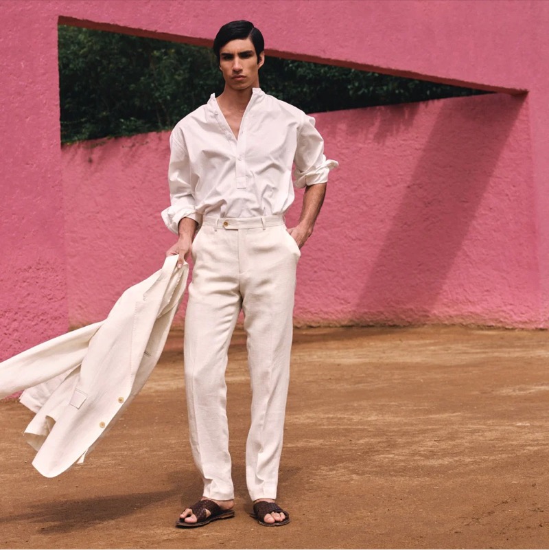 In a crisp all-white outfit, Duncan Yair highlights Todd Snyder Collection’s refined summer look, complete with a textured band collar popover shirt, herringbone suit jacket, and pants.