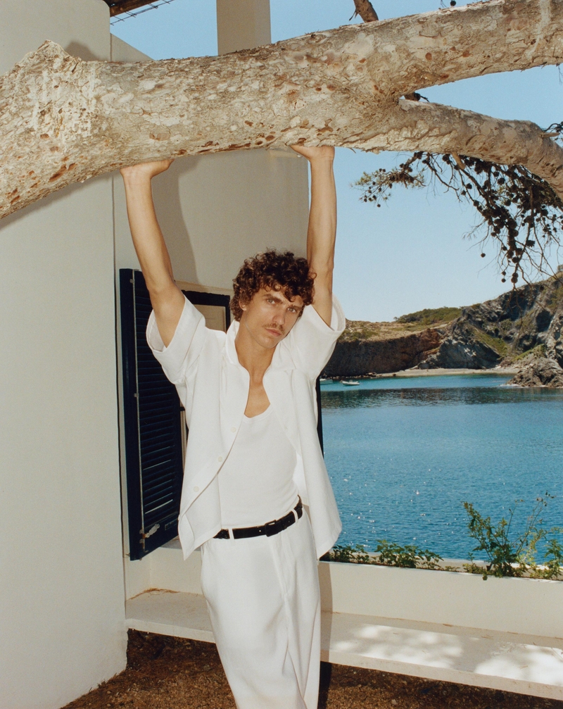 Under the shade of a tree, Grzegorz Chanko embodies relaxed elegance in a white ensemble.