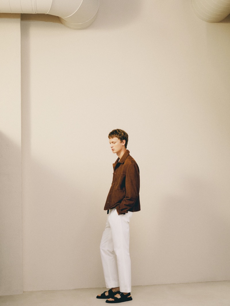 Model Jonas Glöer dons a brown suede jacket with white trousers.