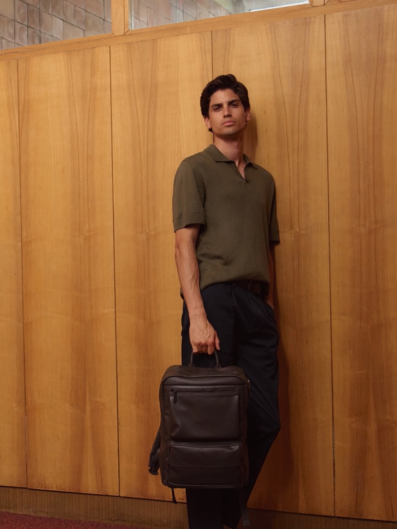 Carrying a faux leather backpack, model Gerard Sabé dons a polo with slacks. 