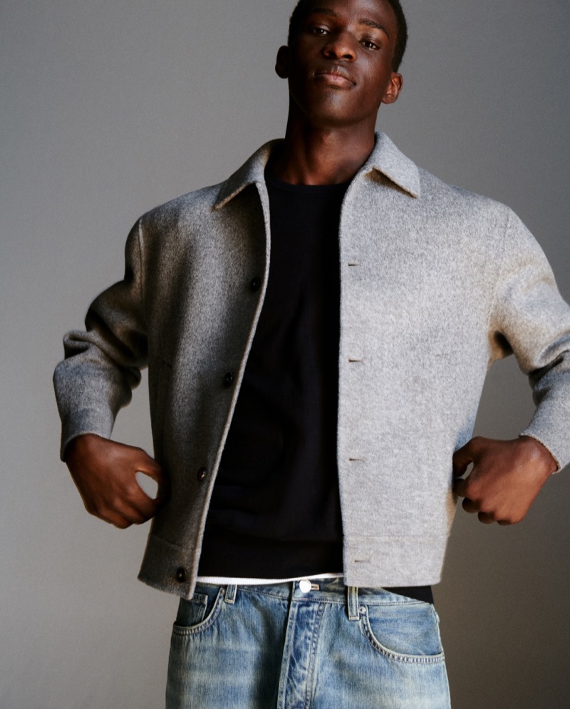 Ayo Hassan sports a grey tailored jacket with distressed jeans.