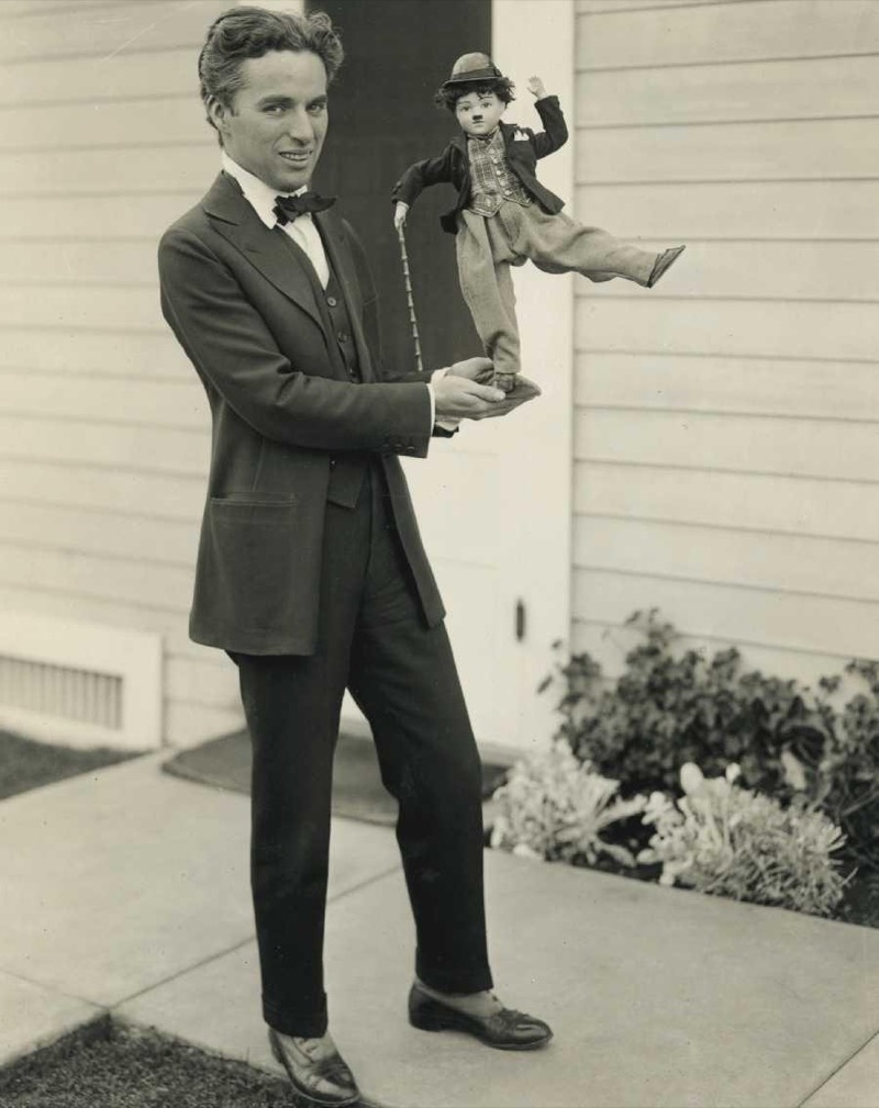 Charlie Chaplin wears a suit, reflecting the more relaxed cuts of the 1910s.