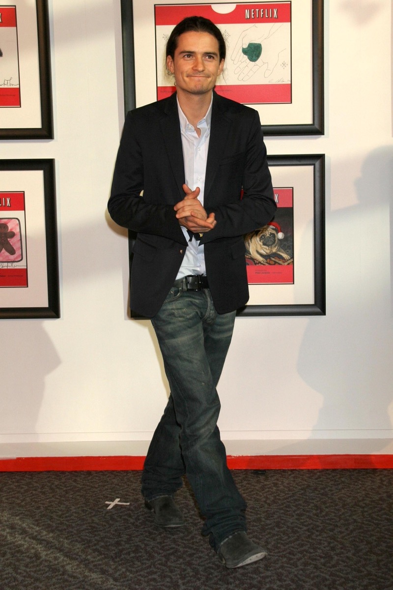 Orlando Bloom wears a popular 2000s outfit, pairing a sports coat with distressed jeans. 